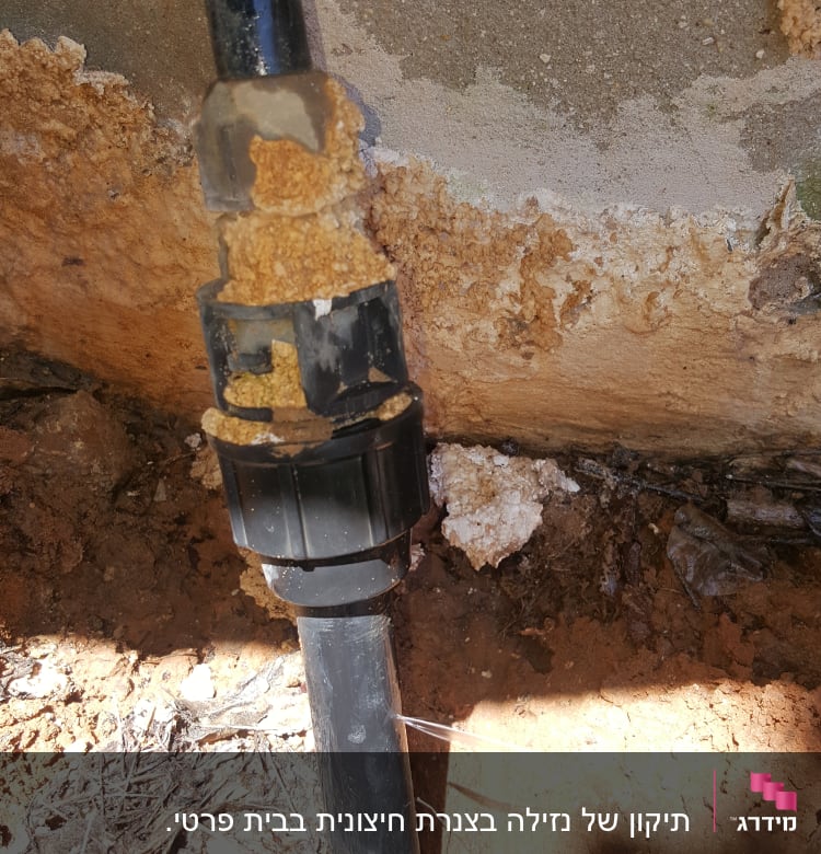 צינור שחור עם נזילה בקיר חיצוני